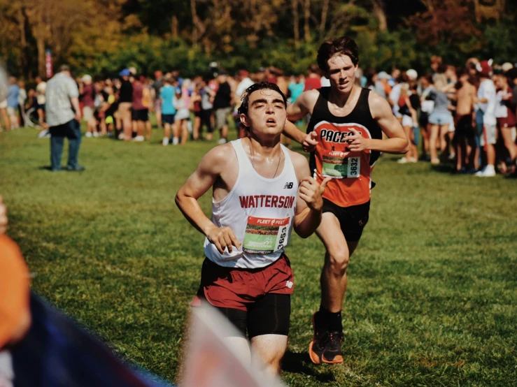 a couple of men running down a grass covered field