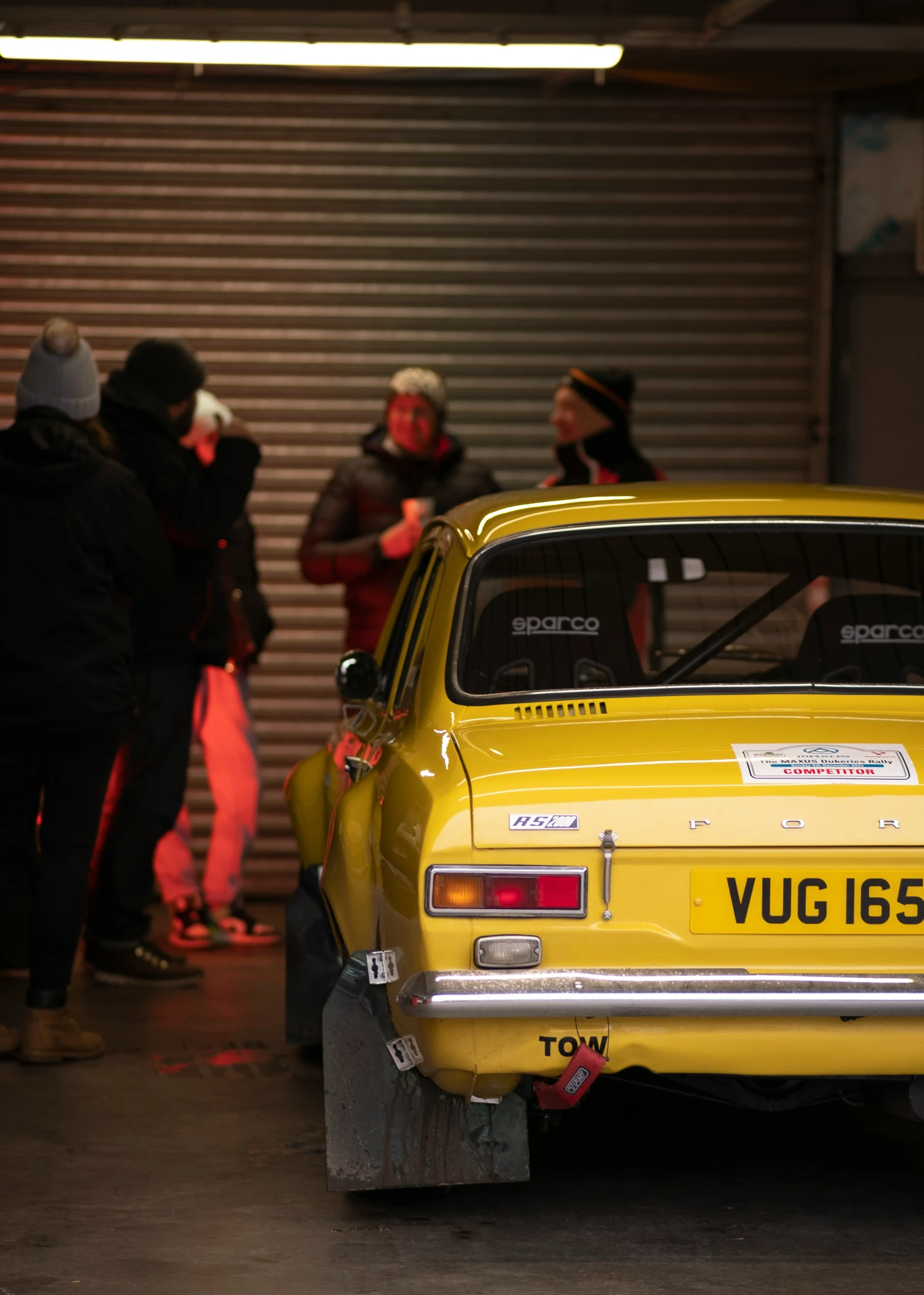 people standing around a yellow volvo car