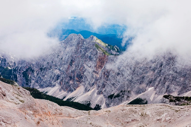 many mountains with snow on them surrounded by clouds