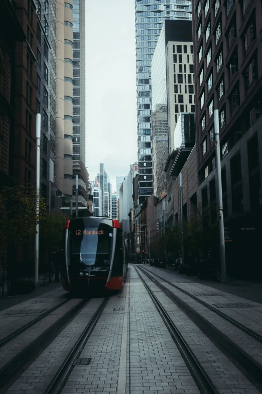 a trolley car is traveling down the street between two very tall buildings