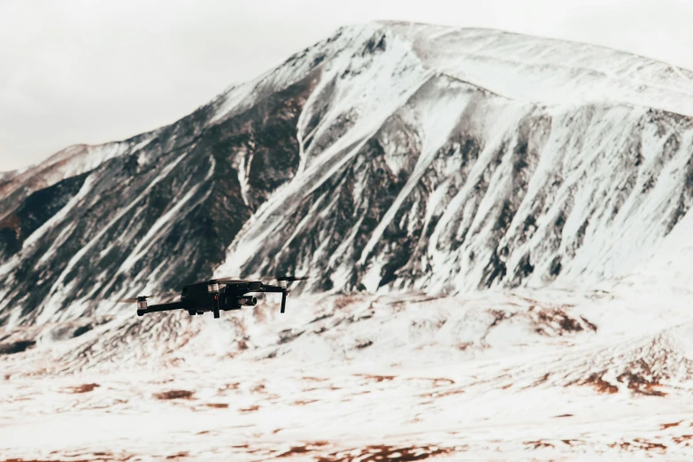 there is a small airplane flying in the sky over a snowy mountain