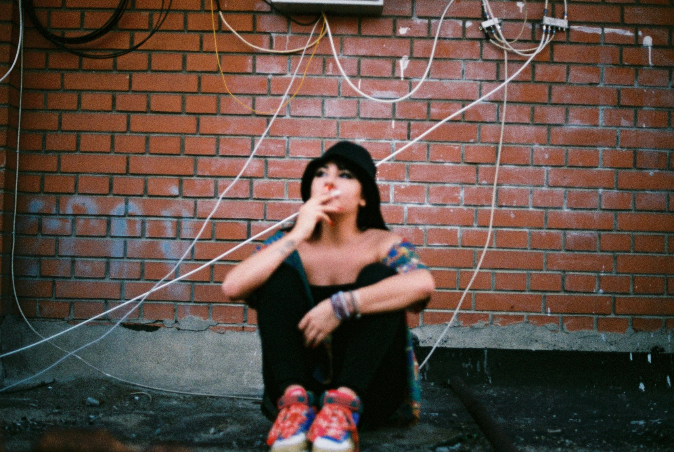 a young woman sitting on the ground and holding her nose next to some wires