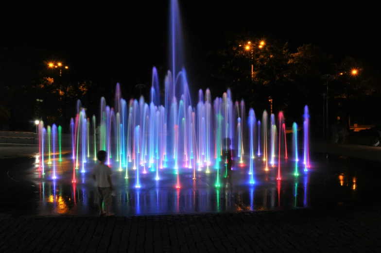 an illuminated fountain of brightly colored lights in a park