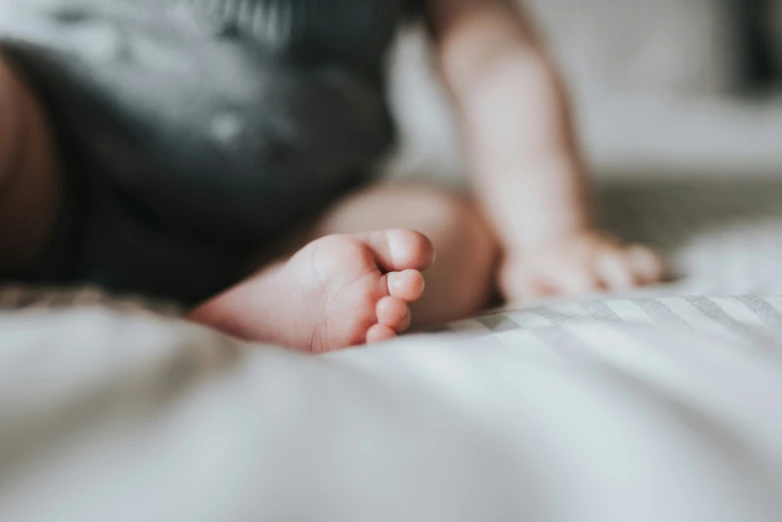 a baby laying on top of a bed with white sheets