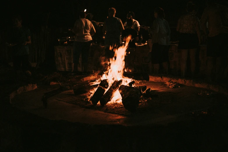 a campfire in the dark with people standing around it