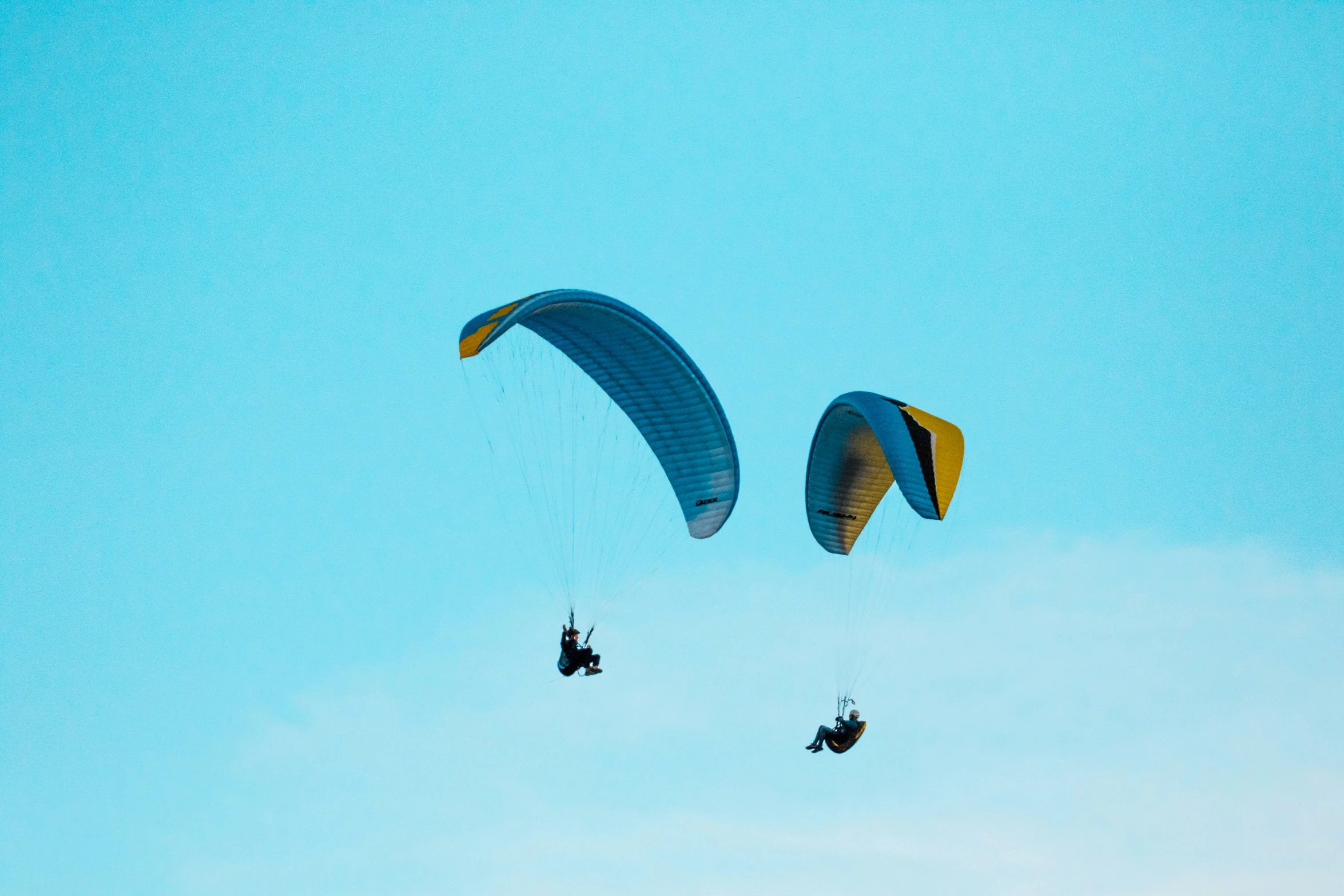 the paragliders are soaring in blue sky together