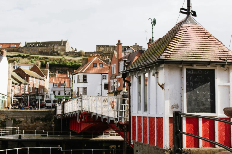 an old style house with a red roof and a wooden bridge