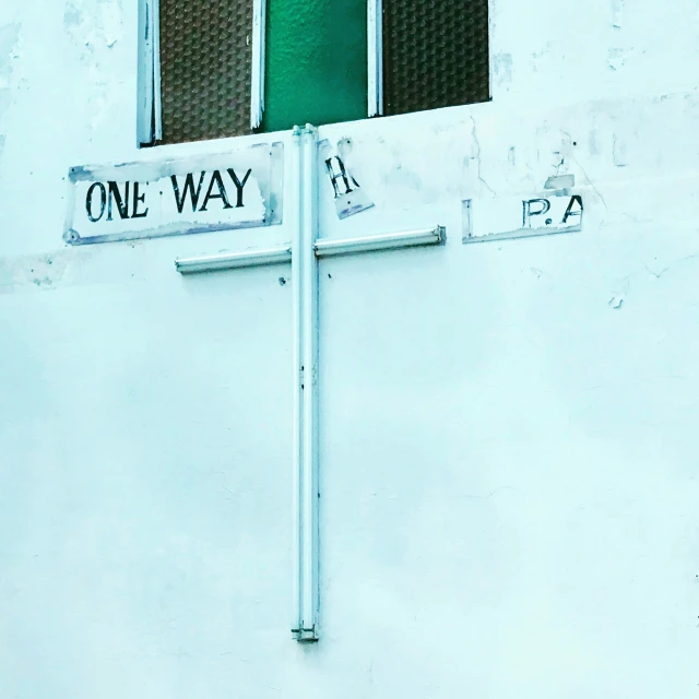 two street signs and a one way sign on a building
