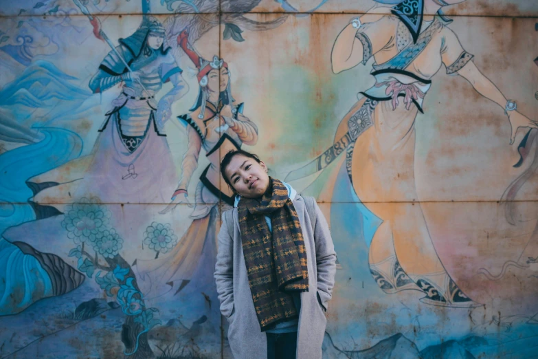 a young man stands in front of a mural