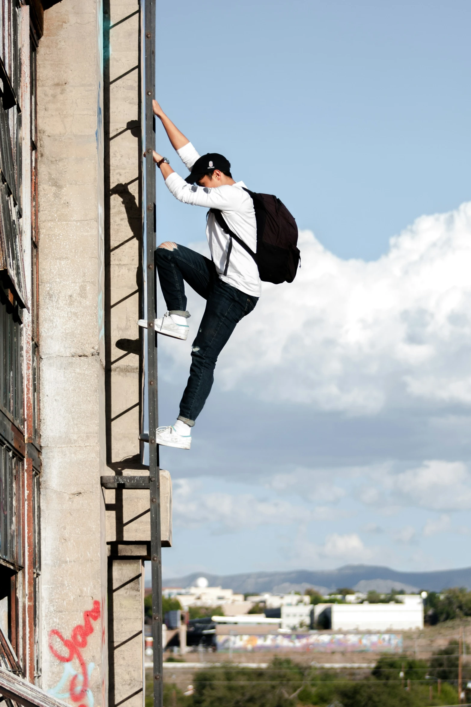 a boy with a back pack climbing down the side of a building