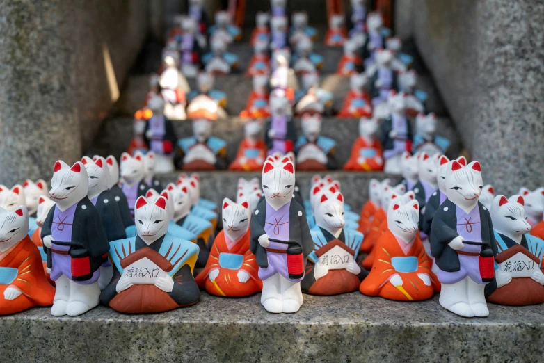 a row of statues of cats wearing colorful clothes