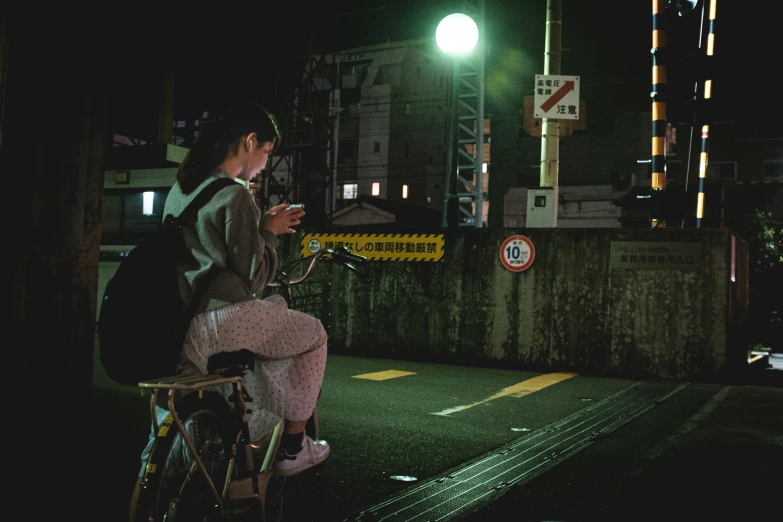 a young woman sits on top of her bike as the light shines down