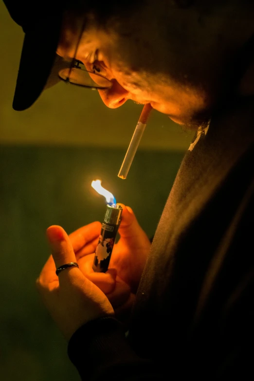 a person holding a lit cigarette near the side of their face