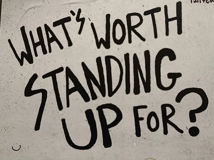 an advertit written on a concrete wall stating what's worth standing up for?
