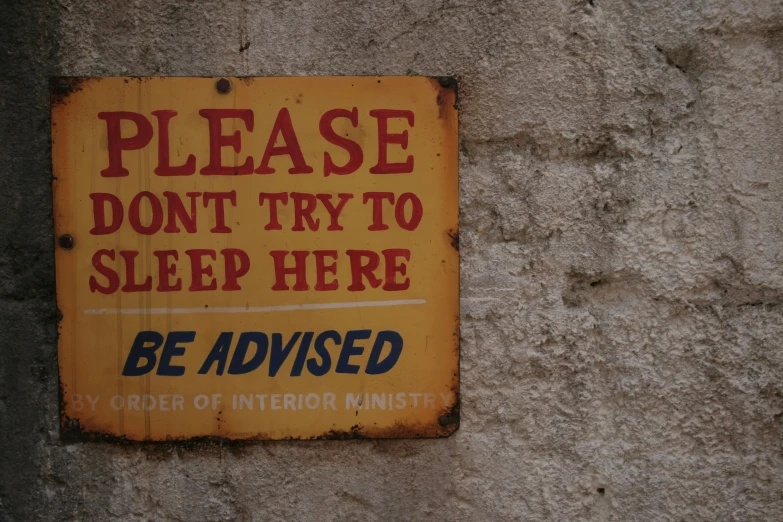 a rusted sign attached to a concrete wall