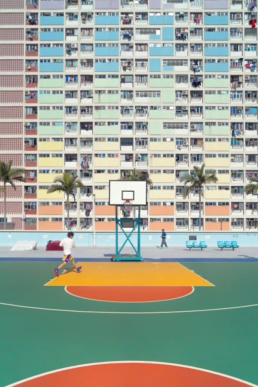 people on an outside basketball court with apartments in the background