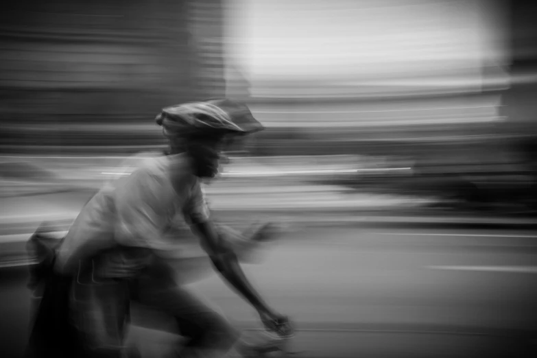 black and white pograph of man riding on street with bike