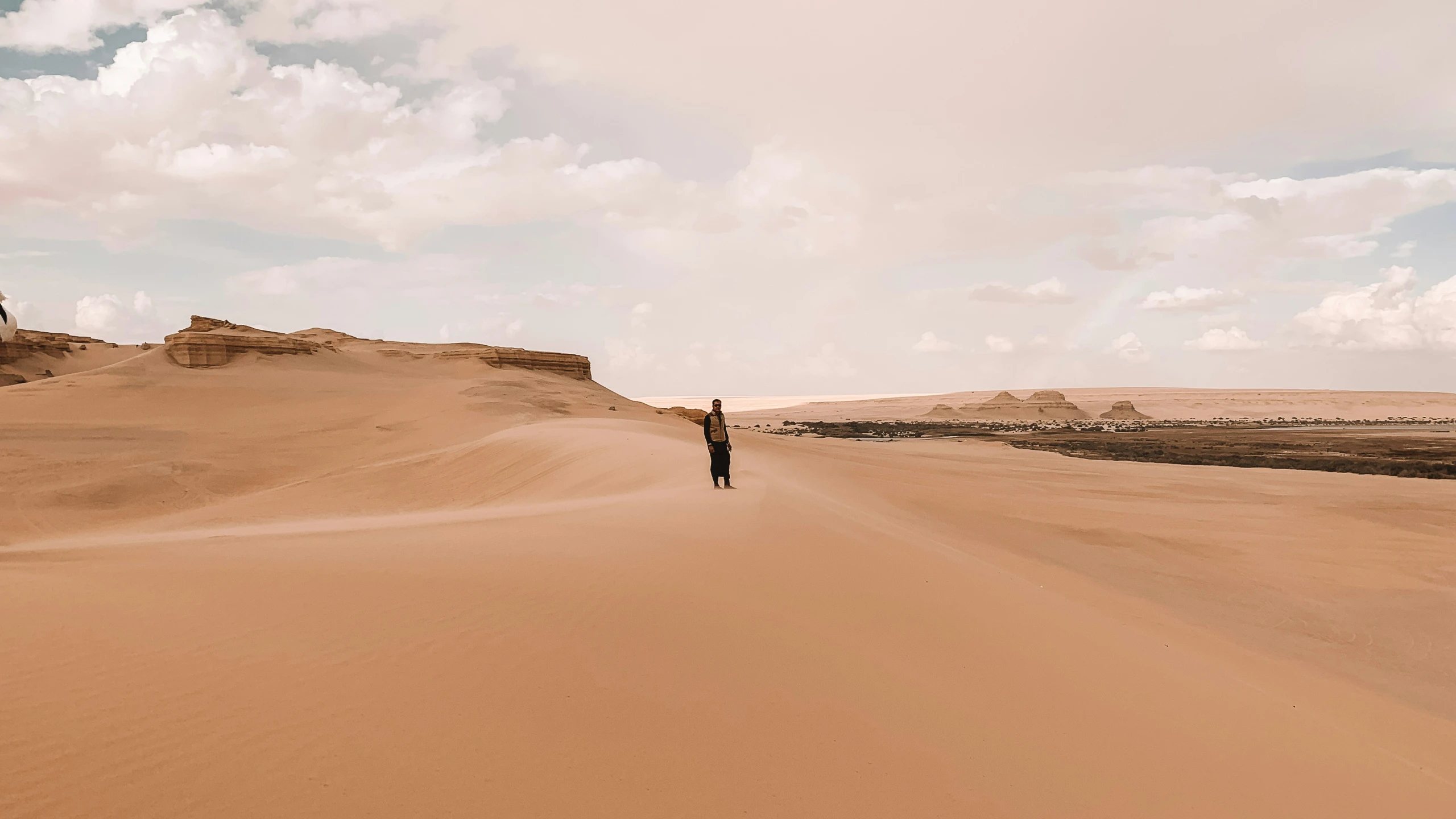 man walking on the sand dunes near the rocks