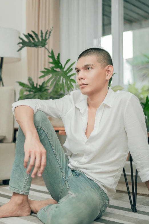 a man wearing white shirt and pants sitting on striped carpet