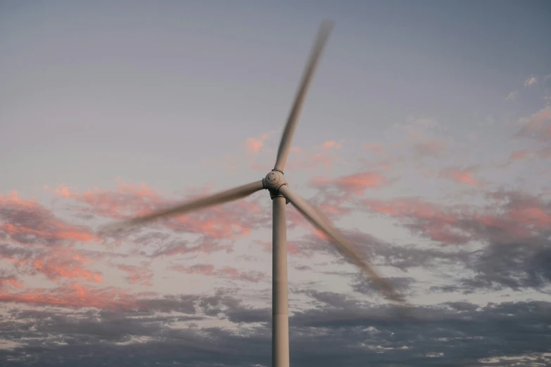 a large wind turbine with a cloudy sky behind it