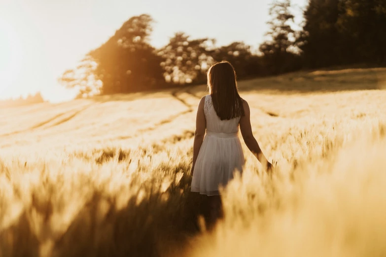 a woman standing alone in an open wheat field