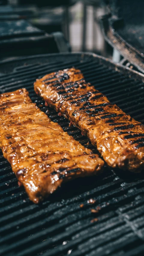 two steaks sit on top of a grill