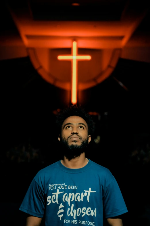 a man with a cross on the top of his shirt