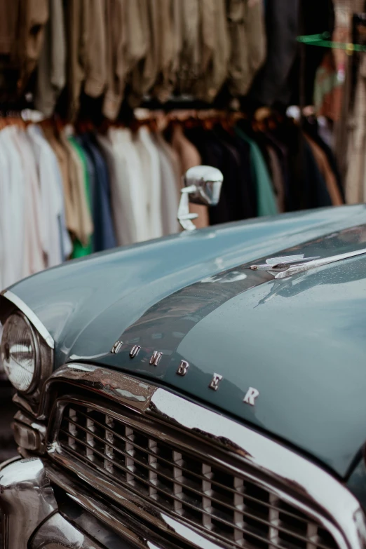 an old fashioned car sitting in front of some clothes