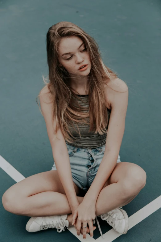 a young woman sits on the tennis court while holding a racquet