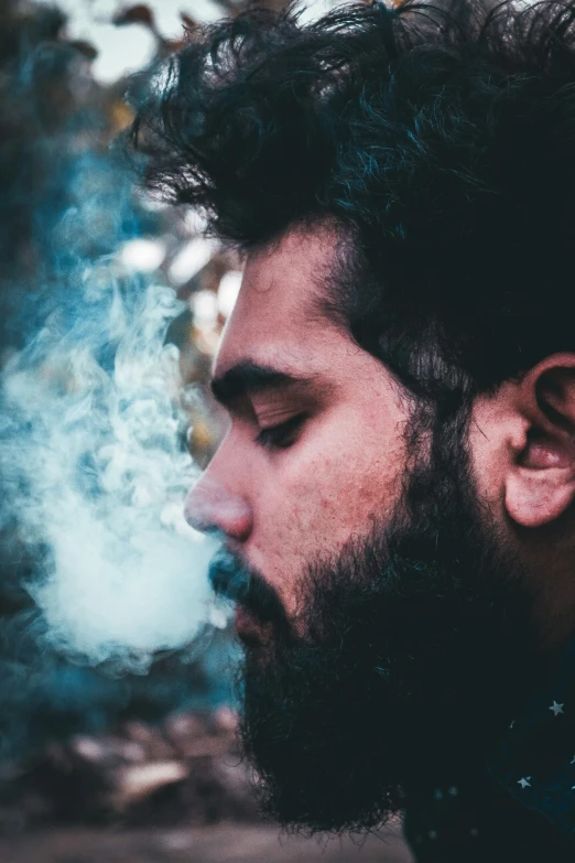 a close up of a man with a beard and a cigarette