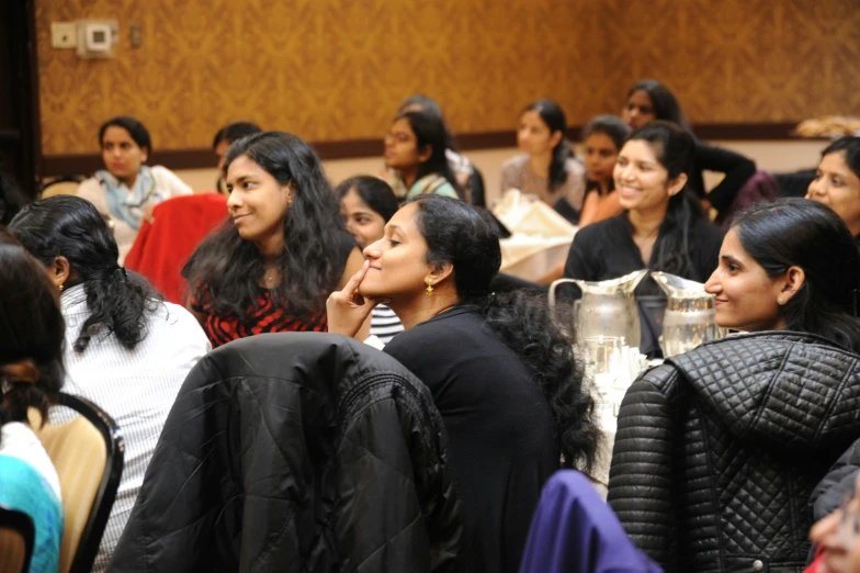 many women sitting in chairs looking at soing