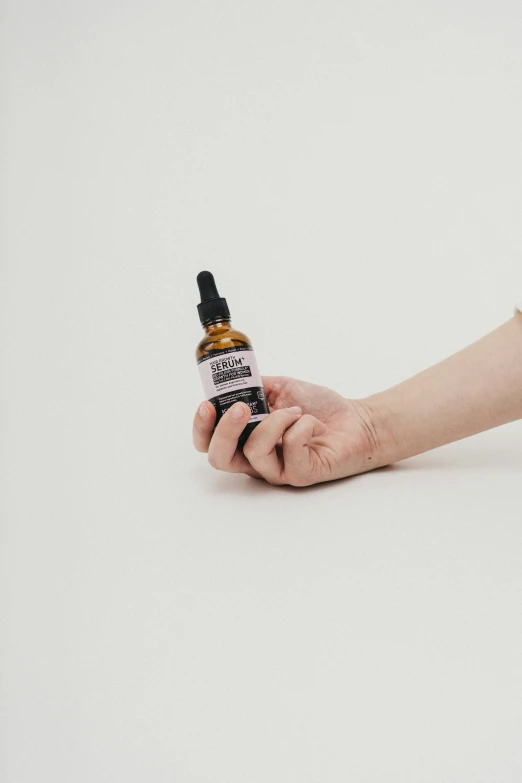 a hand holding a bottle with an orange substance