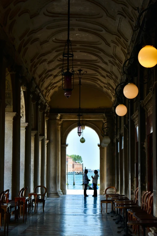 two people walking through an archway between two pillars