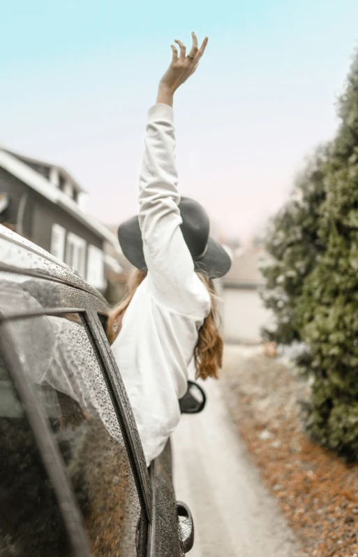 the girl is reaching into the car to catch the sky