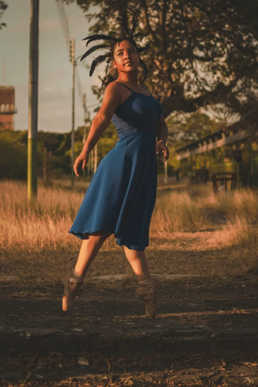 a woman in blue dress kicking around with a soccer ball