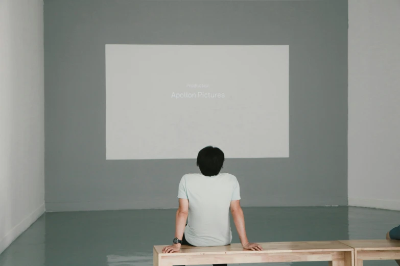 a man sits in front of an interactive screen in the room