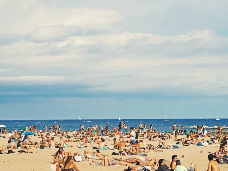 a crowded beach has people sitting on it