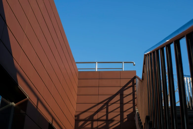 two brown building with railing on top and sky above them