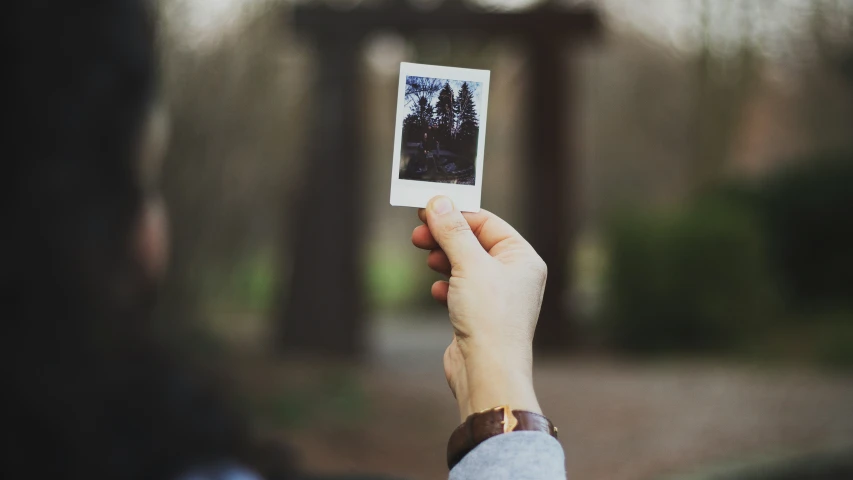 someone holding a polaroid camera over their head