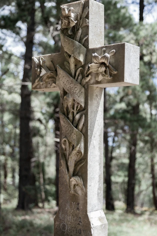 a cross on top of a stone grave in a forest