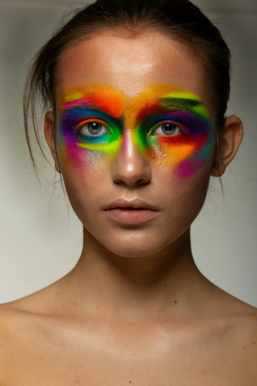 a woman with colorful makeup and rainbow make - up on her face