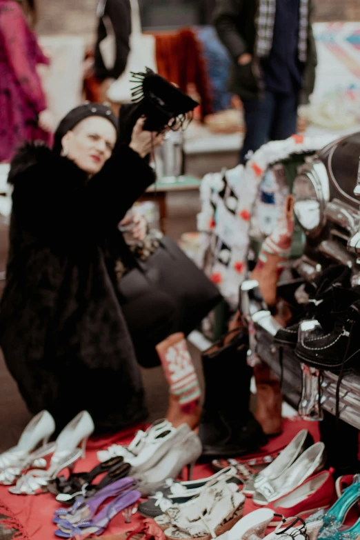 woman with gloves on looking at shoes that she has made