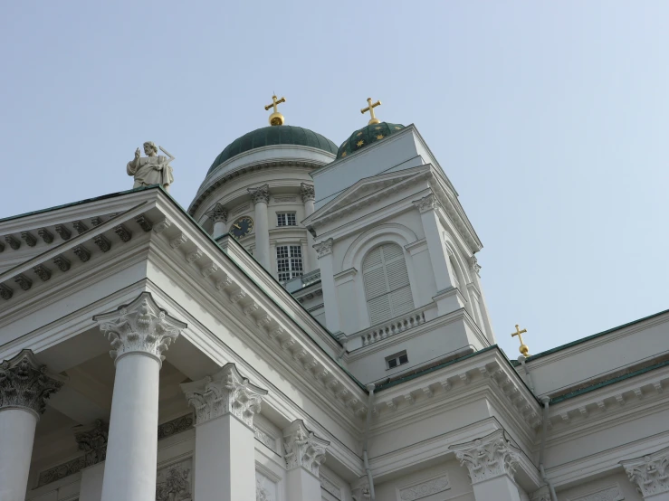 a very ornate white and green building has golden statues on it