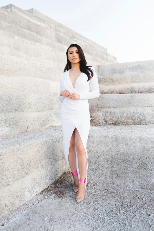 a woman in a white dress standing on some stairs