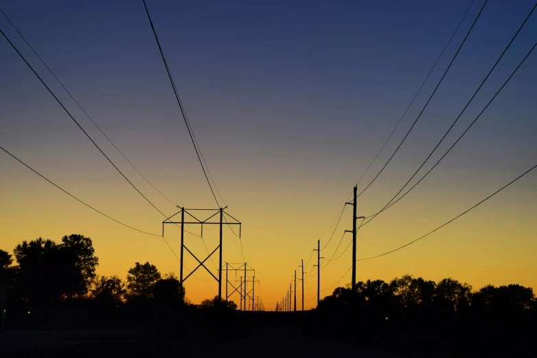 a group of electrical towers silhouetted against an evening sky