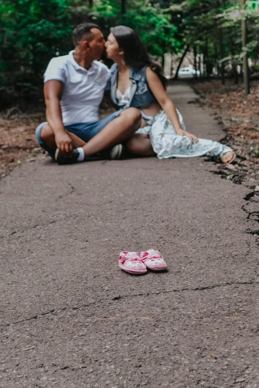 a man is sitting next to his pregnant wife in the park