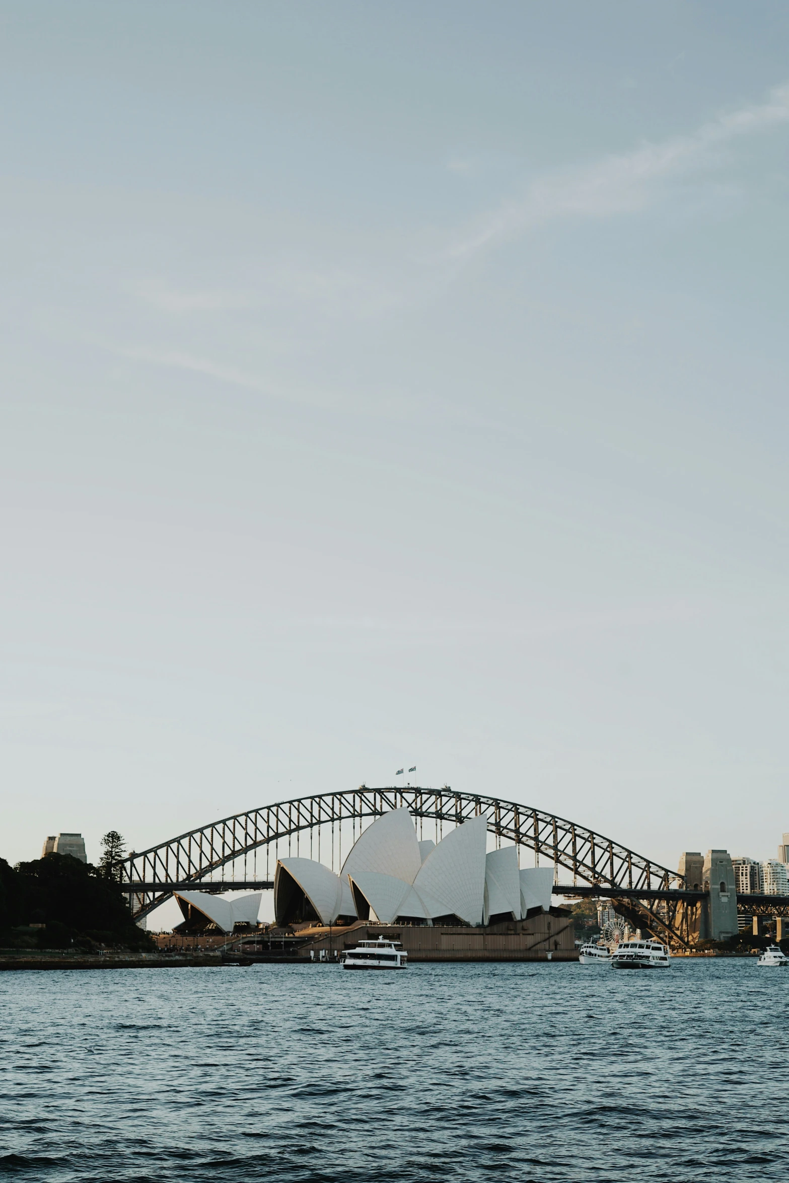 a bridge with some big white sails in the water