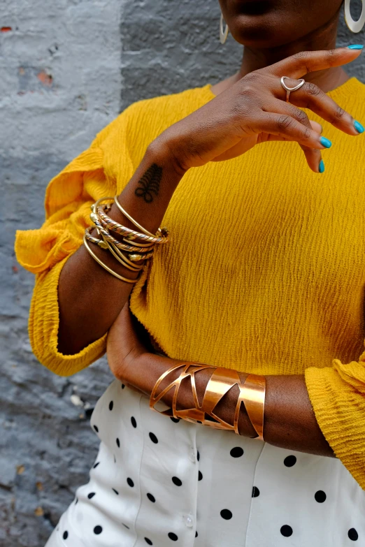 a woman holds her arm with some celets on