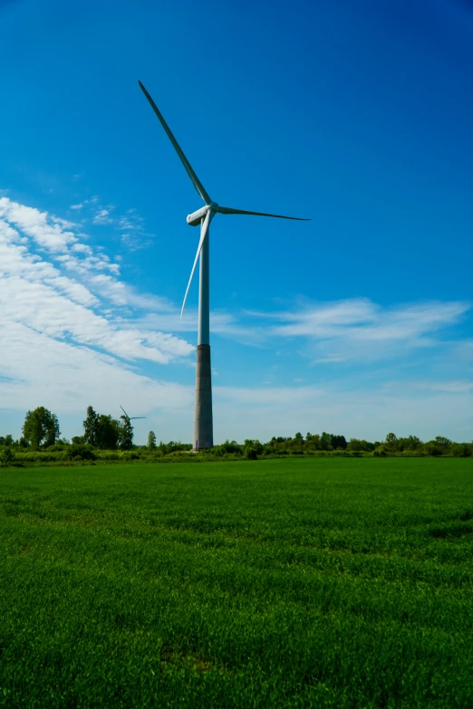 a wind turbine in a grassy field on a sunny day