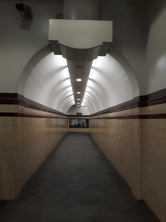 a long brick covered corridor with lights and tile